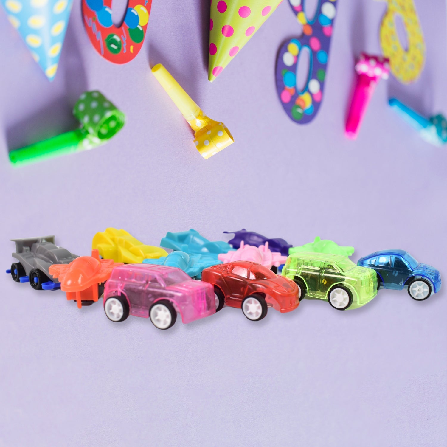 Group of small pull back vehicle toys, including cars and planes, on a white surface.