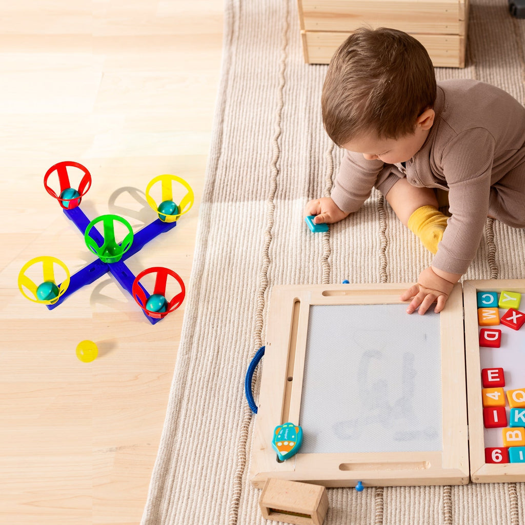 A child aiming a ball into one of the five baskets in the basketball toy set.