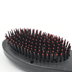 Close-up of the electric hair massager comb's bristles and power button.