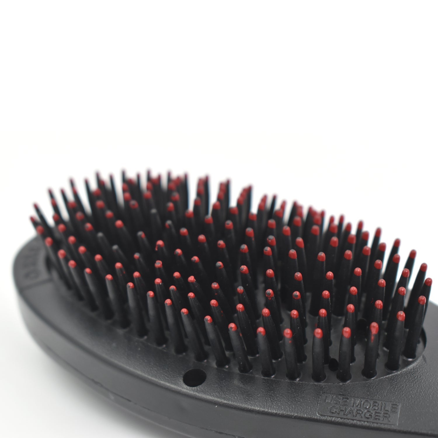 Close-up of the electric hair massager comb's bristles and power button.