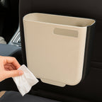 Hanging trash can placed on the floor next to a cabinet, showing its dual use.
