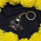 Hand holding golden Shivling keychain showing its size and golden finish
