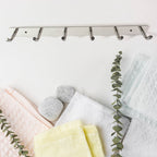 Modern home setting featuring wall mounted stainless steel coat rack with 6 hooks