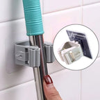 Multiple wall mounted mop & broom holders organizing various cleaning tools.