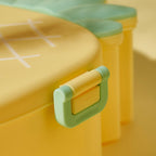 Child's hand opening the vibrant pineapple bento lunch box to reveal compartments.