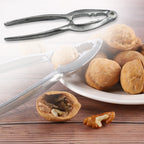 Hand holding the compact stainless steel nut cracker, demonstrating its portability.