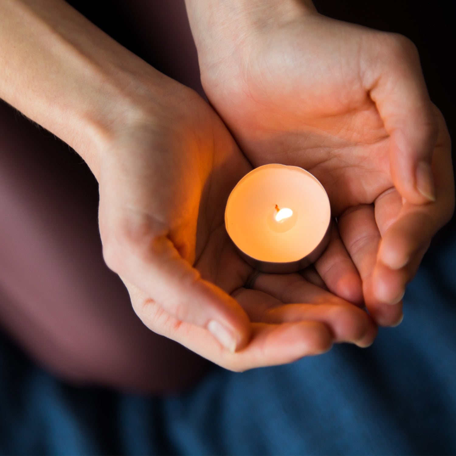 A hand holding a rose tealight candle, highlighting its size and intricate petal details.
