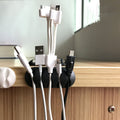 Cable organiser clips in black, shown holding multiple wires neatly on a desk.