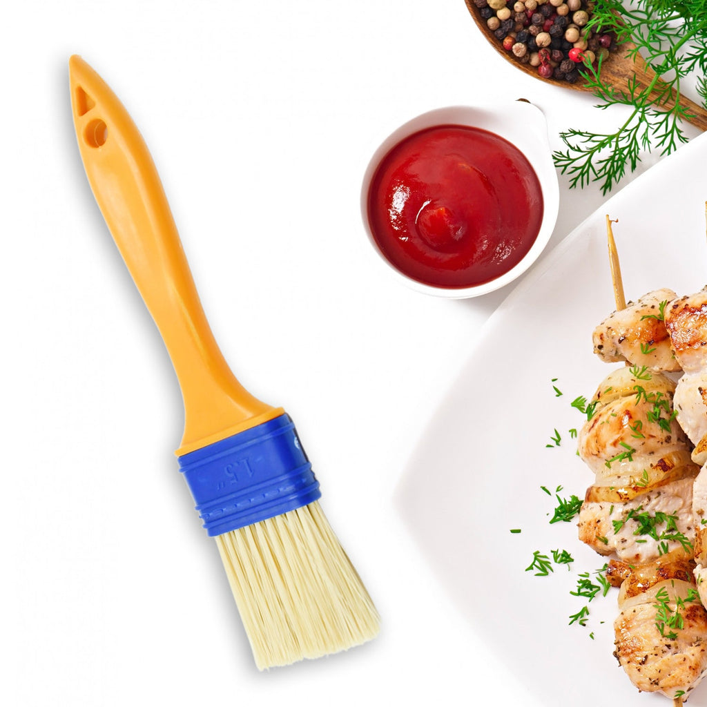A red cooking brush evenly basting meat on a grill.