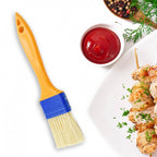 A red cooking brush evenly basting meat on a grill.