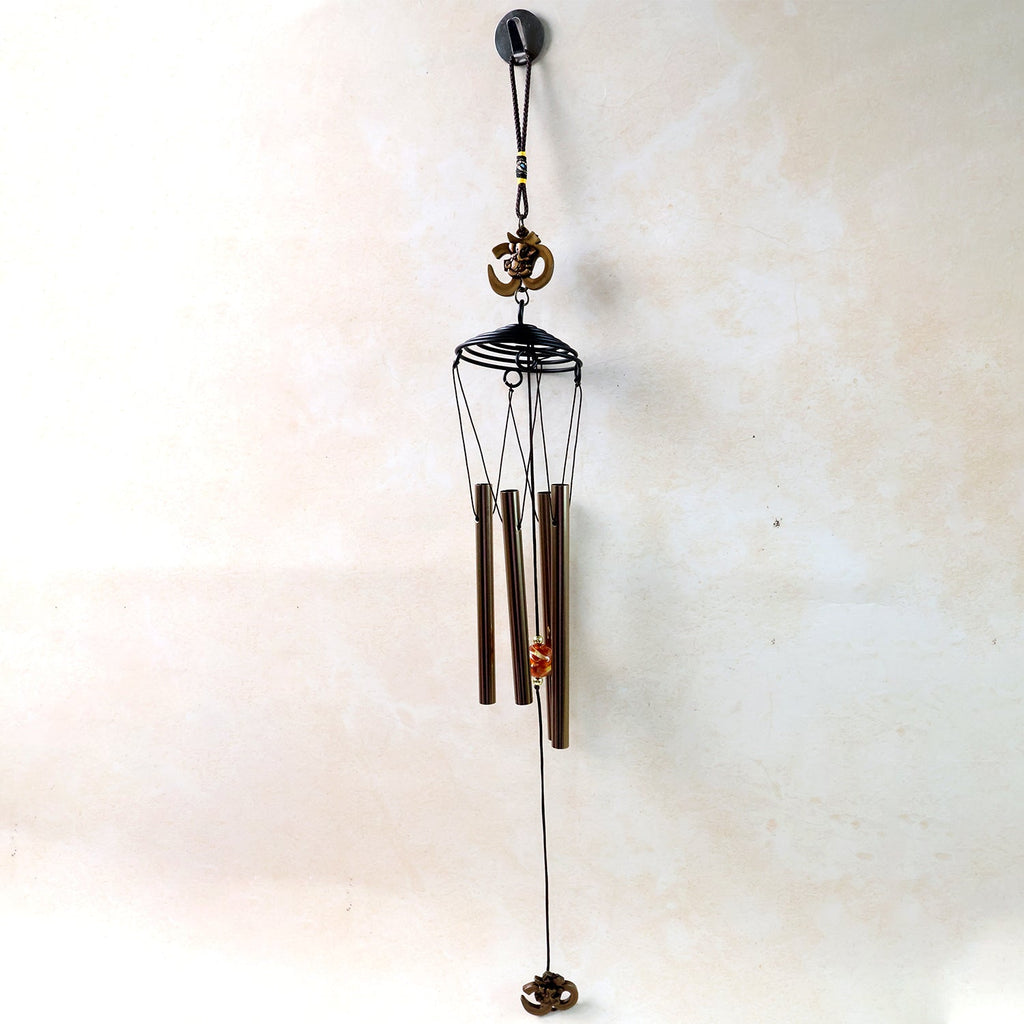 Metal Om symbol wind chime hanging on a wooden porch