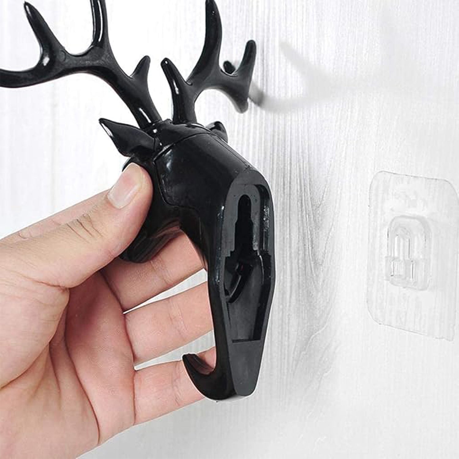 Deer head wall hook displayed with a hand for scale, emphasizing its compact size.