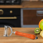 Kitchen vegetable peeler with wooden handle resting on cutting board