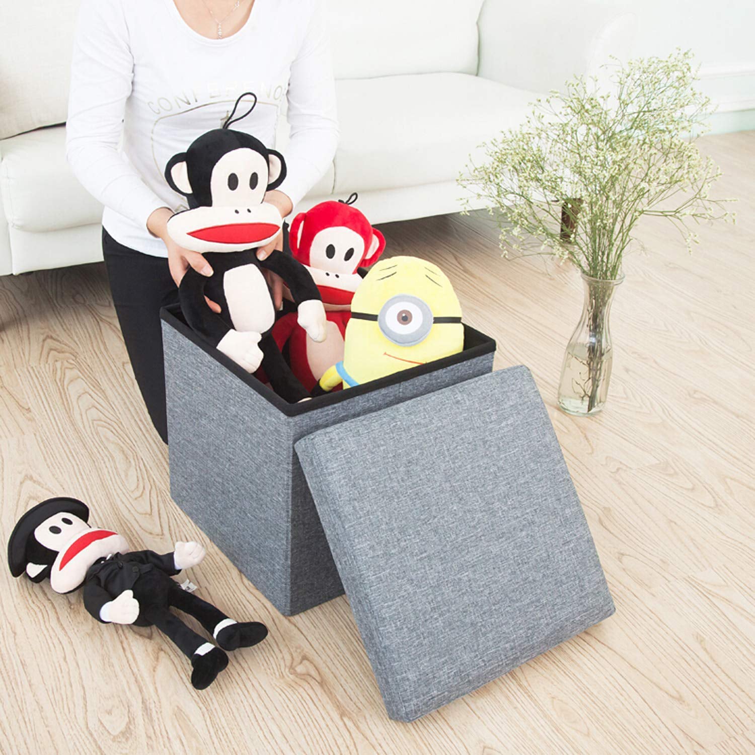 A stylish grey foldable storage stool with a comfortable cushion top, perfect for living room organization.