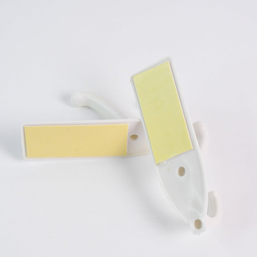 Easy application of a self-adhesive wall hook on a smooth surface with hanging items.