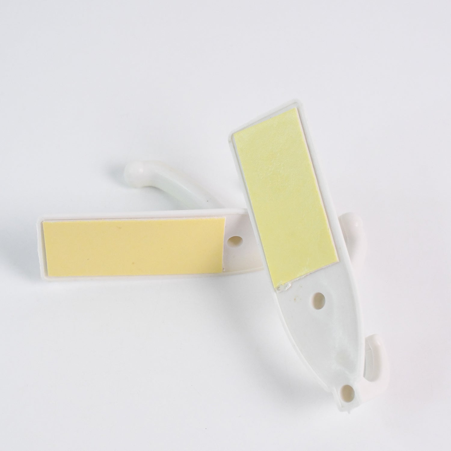 Easy application of a self-adhesive wall hook on a smooth surface with hanging items.