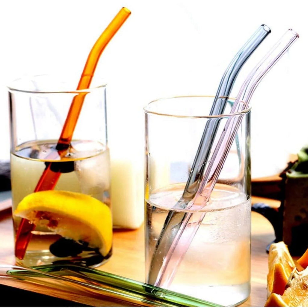Five reusable clear glass drinking straws arranged side by side