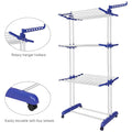 Foldable stainless steel clothes drying rack with wheels and side hanger arms holding garments indoors