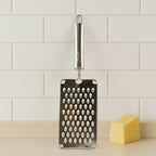 Flat handheld stainless steel vegetable grater in use grating carrots
