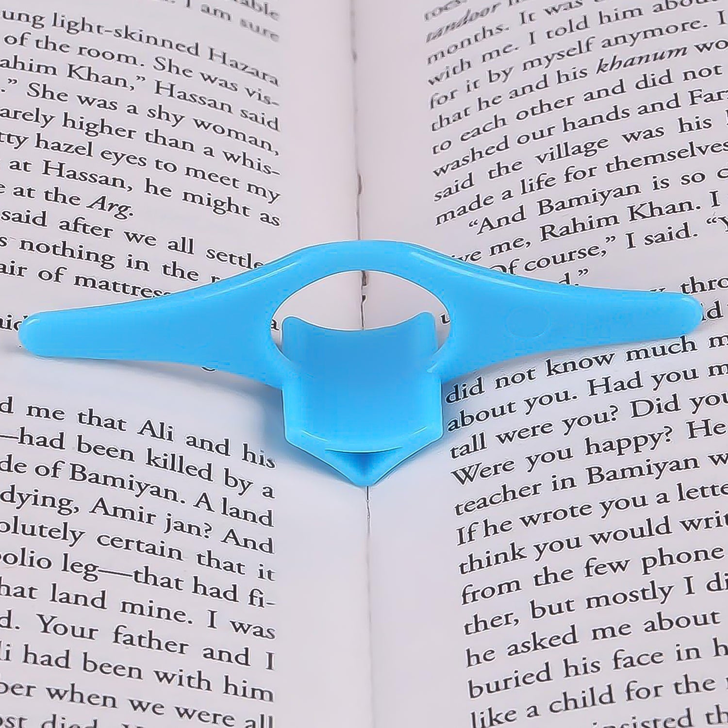 Person comfortably reading a book held open by the plastic thumb page holder.