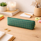 Hand holding portable green grid pencil pouch for travel or school.