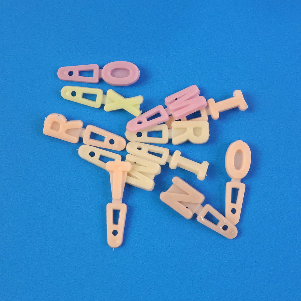 Assorted alphabet craft beads arranged to form words on surface.