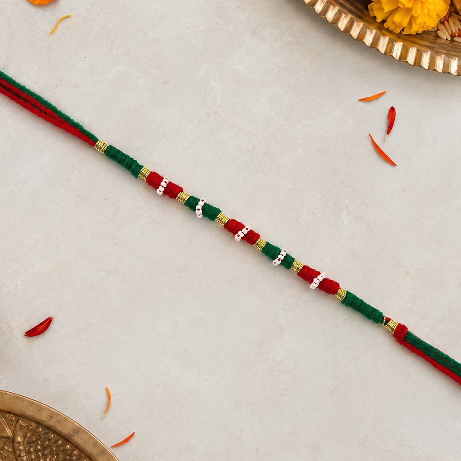 Cotton thread rakhi in red, green, and white with intricate design
