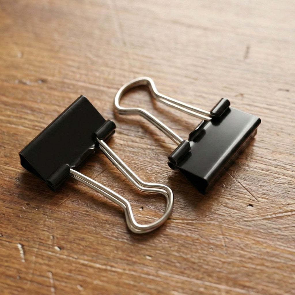 Black coated metal binder clip close-up showing spring mechanism