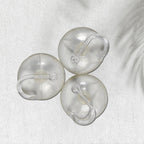 Two transparent suction hooks with strong hold on a bathroom tile wall.