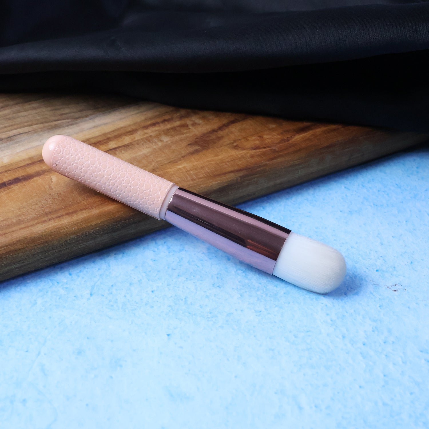 Angled view of soft makeup brush showing synthetic bristles and ergonomic handle