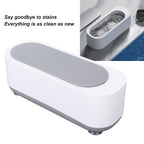 Compact ultrasonic cleaner with a sparkling ring and earrings inside after cleaning.
