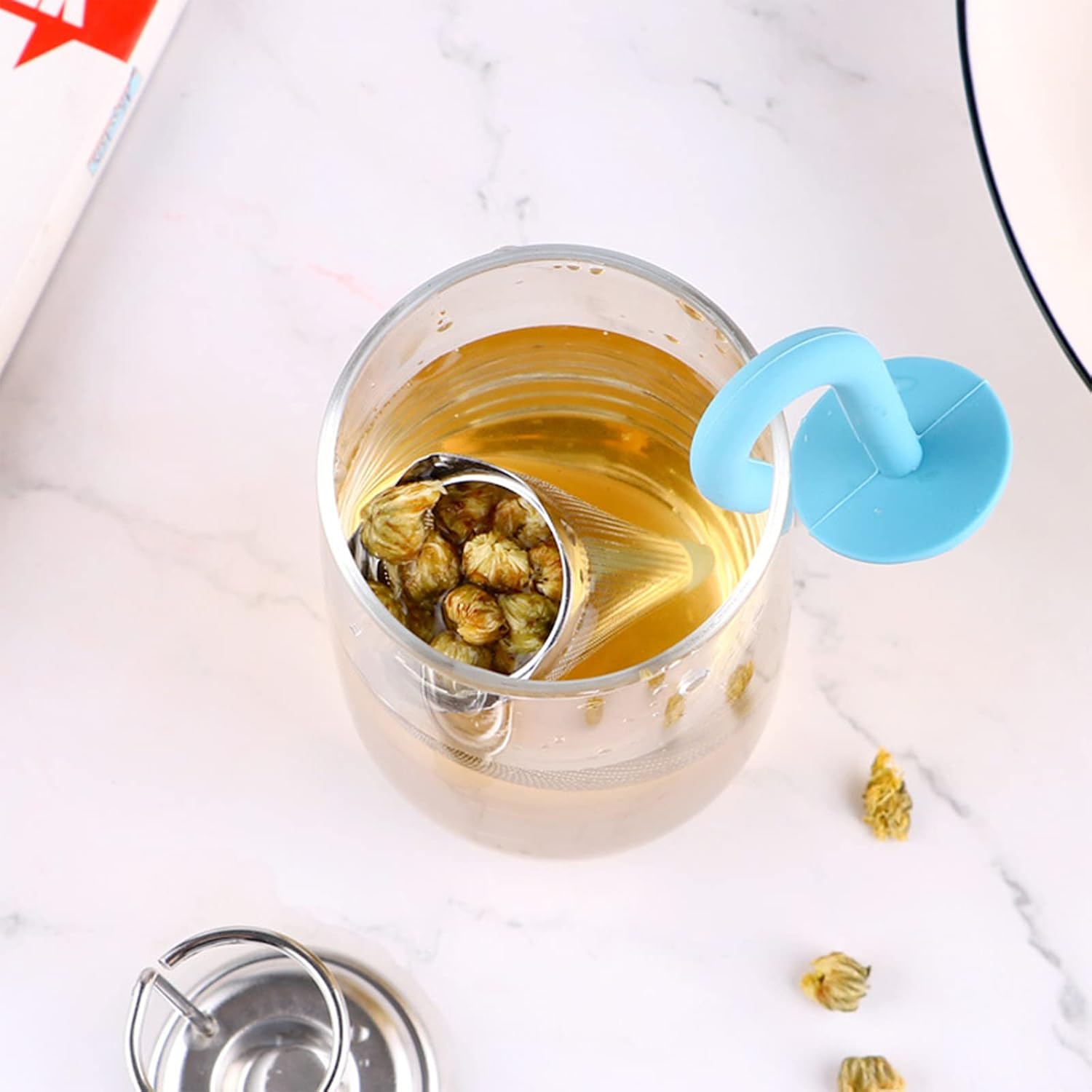 An umbrella tea strainer hanging on the rim of a teacup, ready to infuse.