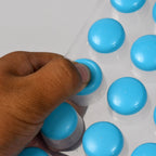 Multiple colorful round silicone ice cube trays filled with frozen ice spheres.