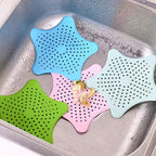 Star-shaped silicone hair catcher actively collecting hair in a bathroom basin.
