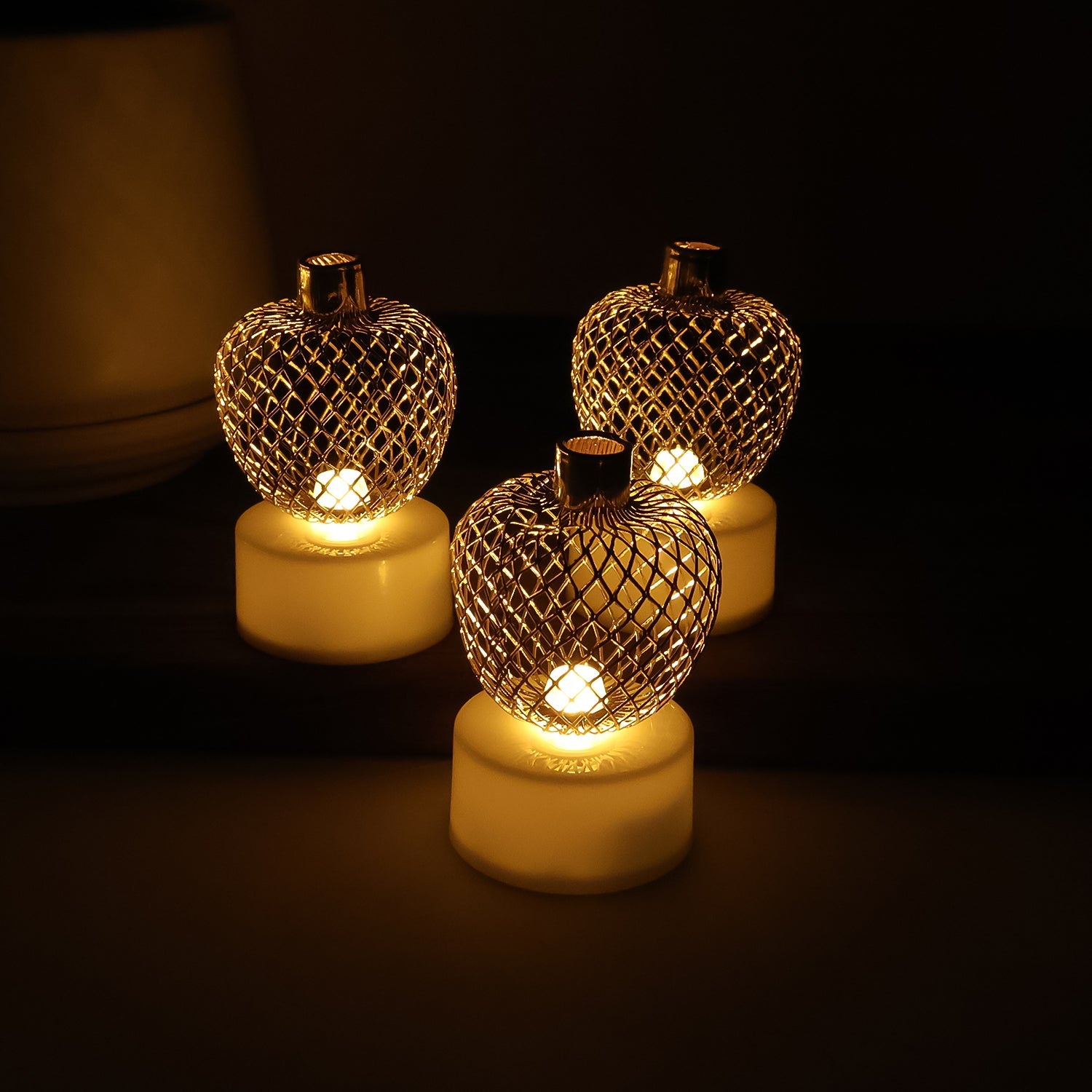 Decorative apple shaped LED tealight candle set lit on a table