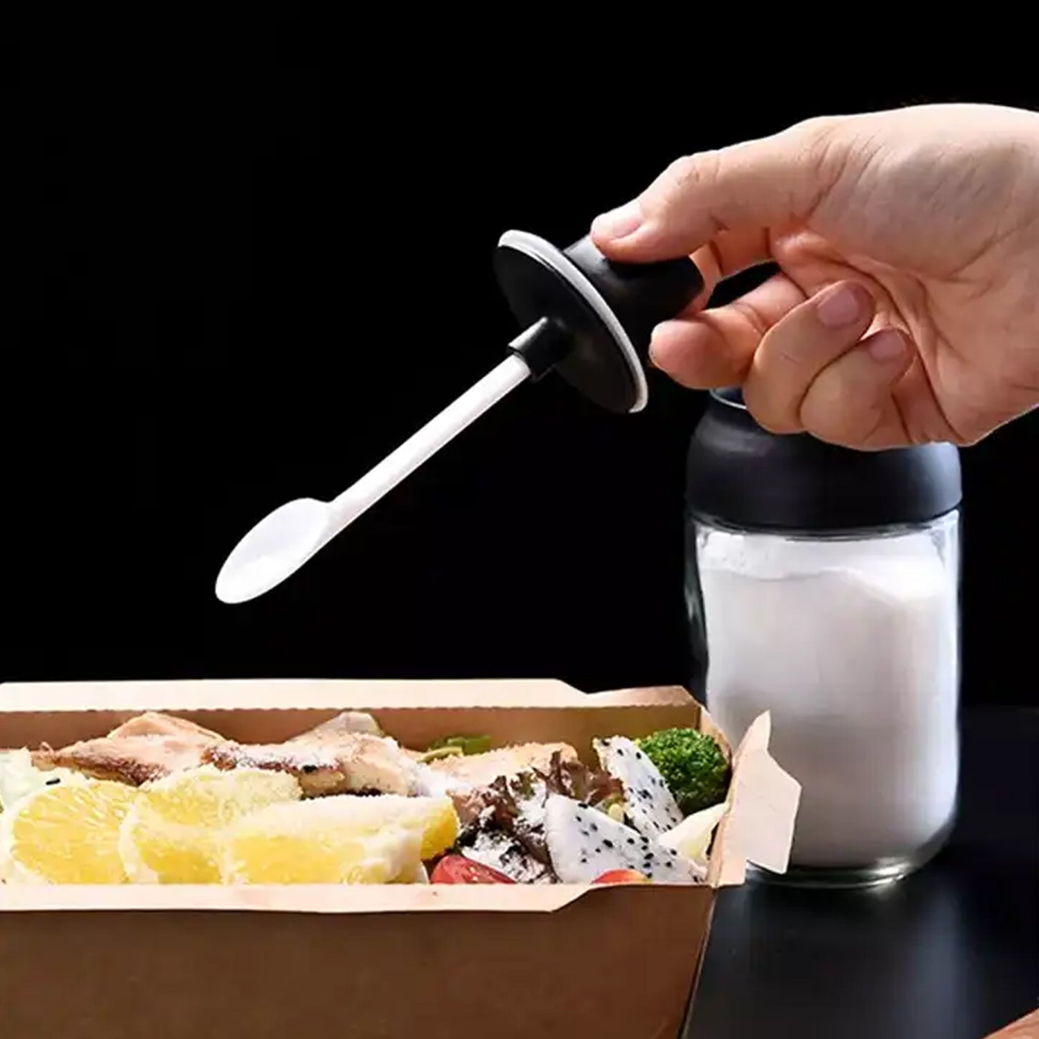 Detail view of the durable glass seasoning jar with its integrated spoon.