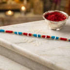 Decorative red rakhi thread bracelet with gold accents