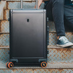 Set of four flexible silicone suitcase wheel covers in black, neatly packaged.