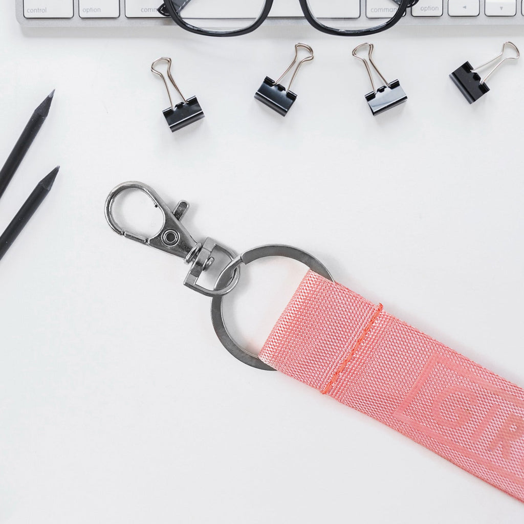 Detail view of Girl Power fabric ribbon keychain with embossed text and metal keyring