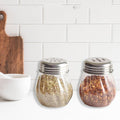 Oregano & Chilli Flakes Dispenser Set with clear plastic body and stainless steel lids on kitchen counter