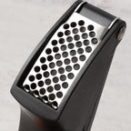 Garlic crusher utensil with fresh garlic cloves ready for pressing