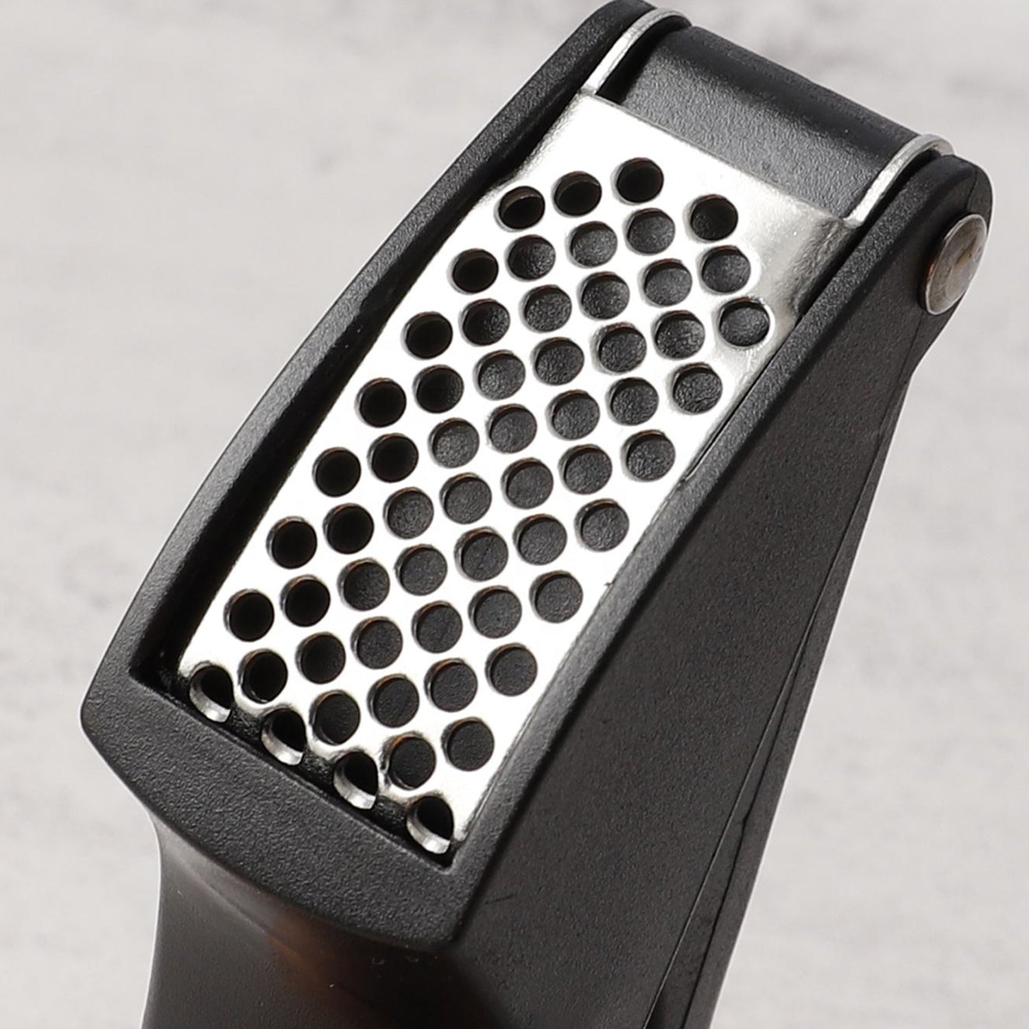 Garlic crusher utensil with fresh garlic cloves ready for pressing