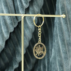 Hand holding the Maa Durga golden oval frame metal keychain