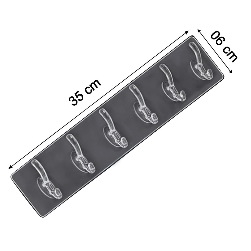 Elegant golden and transparent 6-pin hooks providing storage on a bathroom wall.