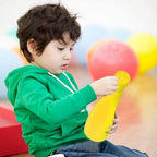 Happy children enjoying an outdoor play equipment bowling game, improving motor skills.