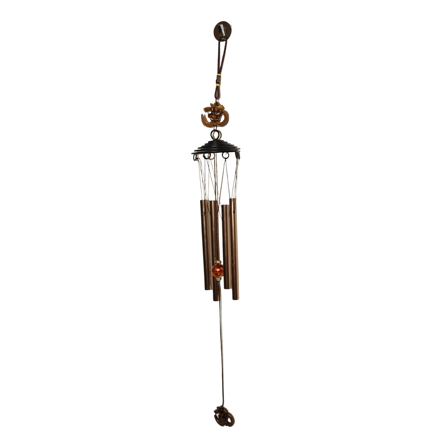 Side view of metal wind chime with Om symbol against green background