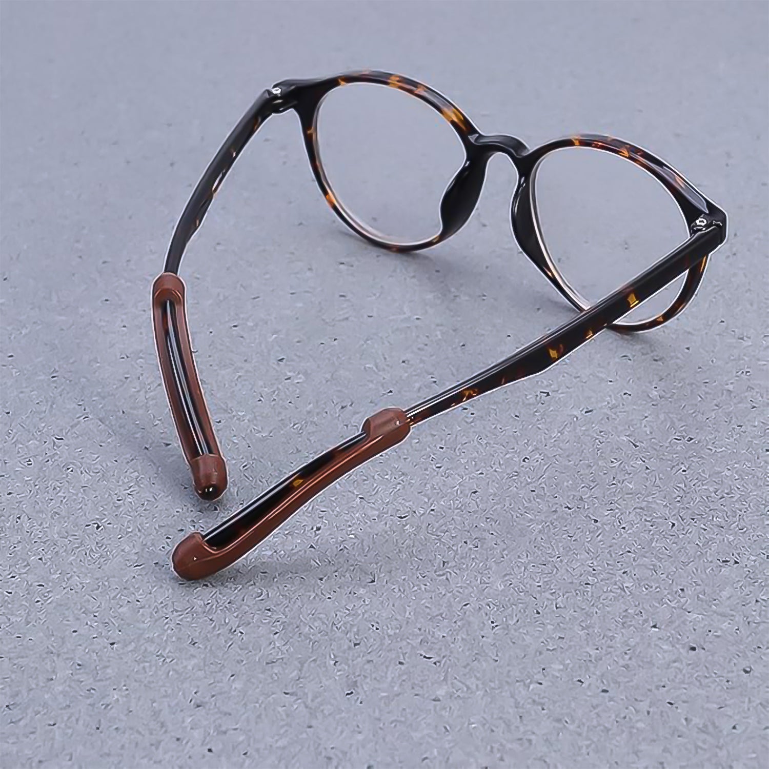 Silicone ear grips attached to eyeglass arms, demonstrating how they prevent glasses from slipping.
