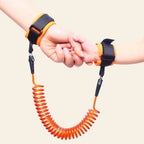 Happy child wearing a blue Baby Safety Harness with an adult hand holding the anti-lost wrist link.