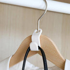 Stack of white plastic hanger connector hooks ready for use.