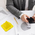 A flexible pyramid mobile stand in black, holding a smartphone upright on a desk.